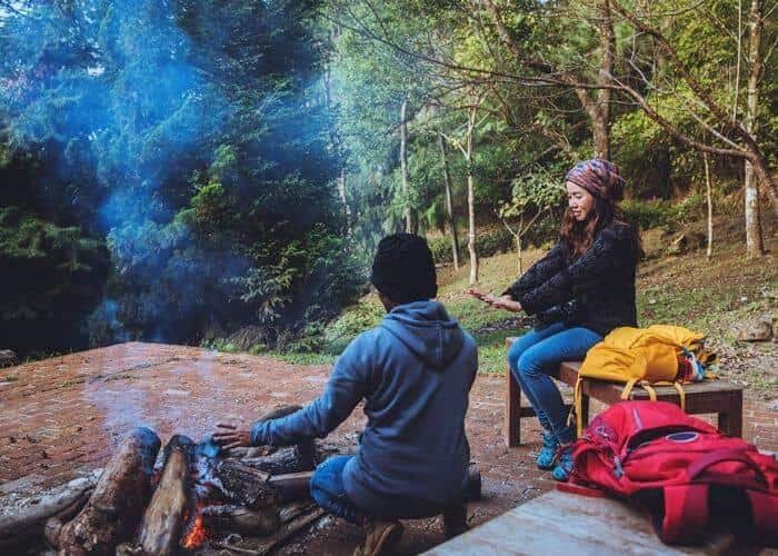 Two people sitting in front of a campfire